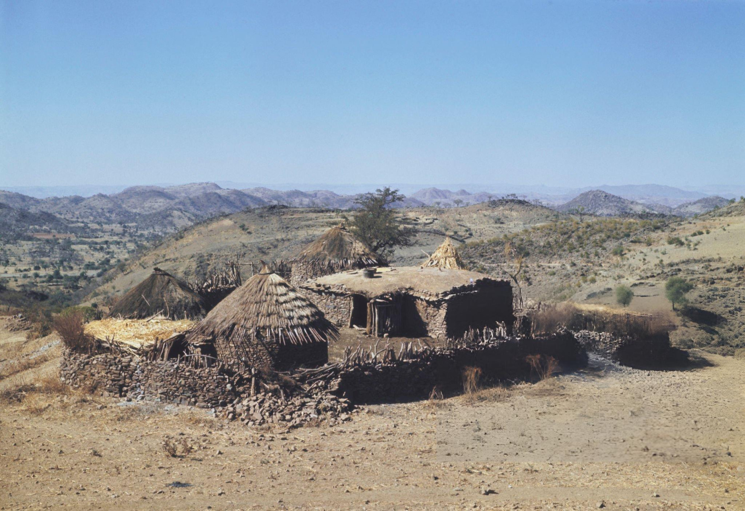 Huts and dwellings of a village located on the edge of an escarpment overlooking a valley in  Tigray.