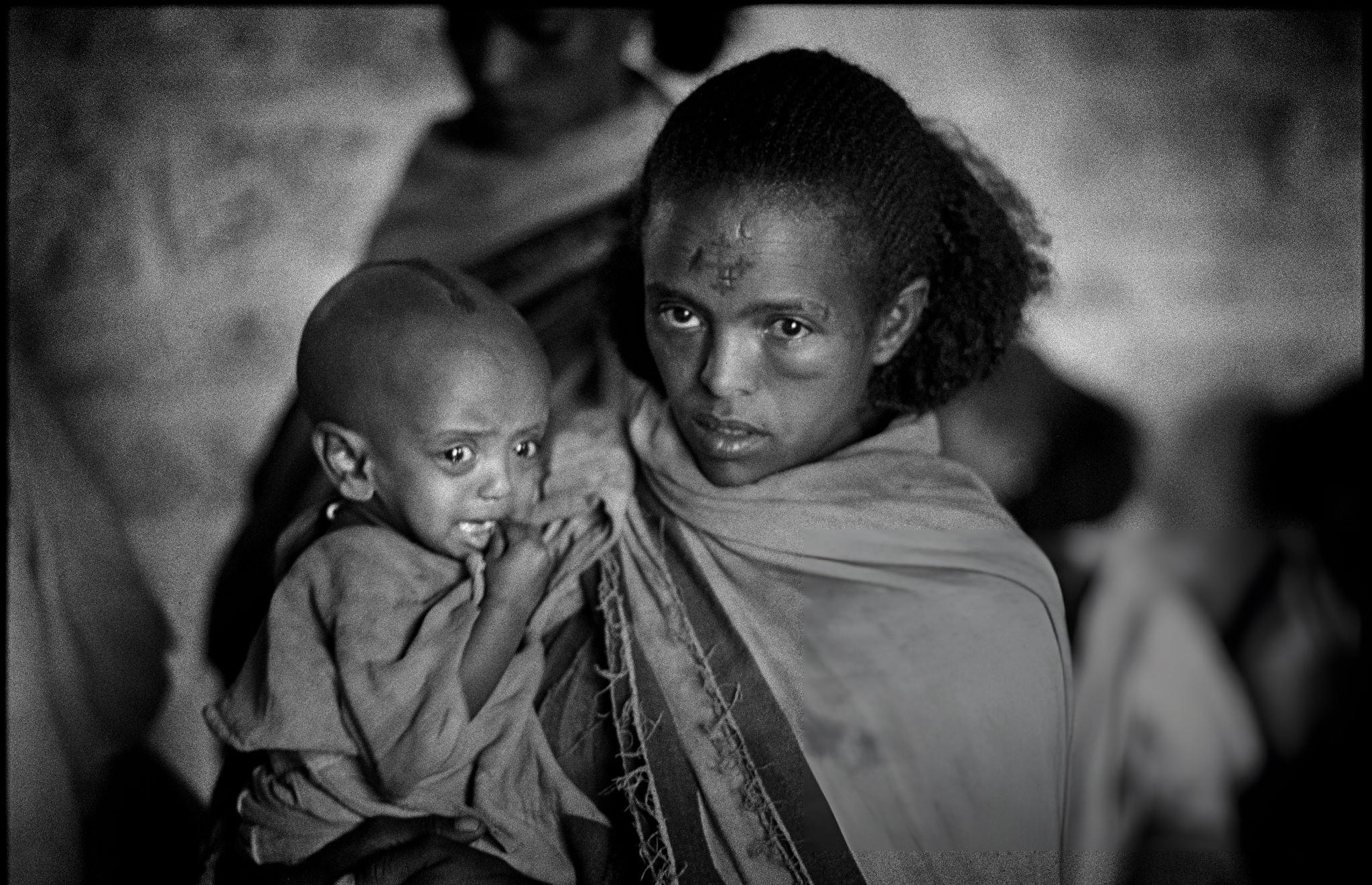 View of an unidentified woman as she holds a crying infant at a famine relief center on the outskirts of Mekelle, Tigray.
